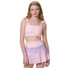 girl wearing flare tennis skirt with matching pink sports bra front view
